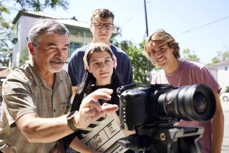 A faculty member shows students how to use a camera.