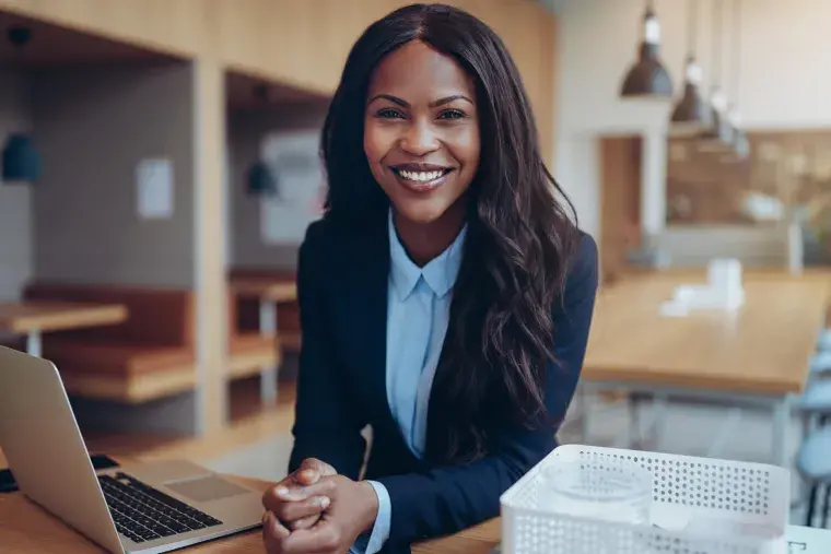 A student with a laptop smiles.