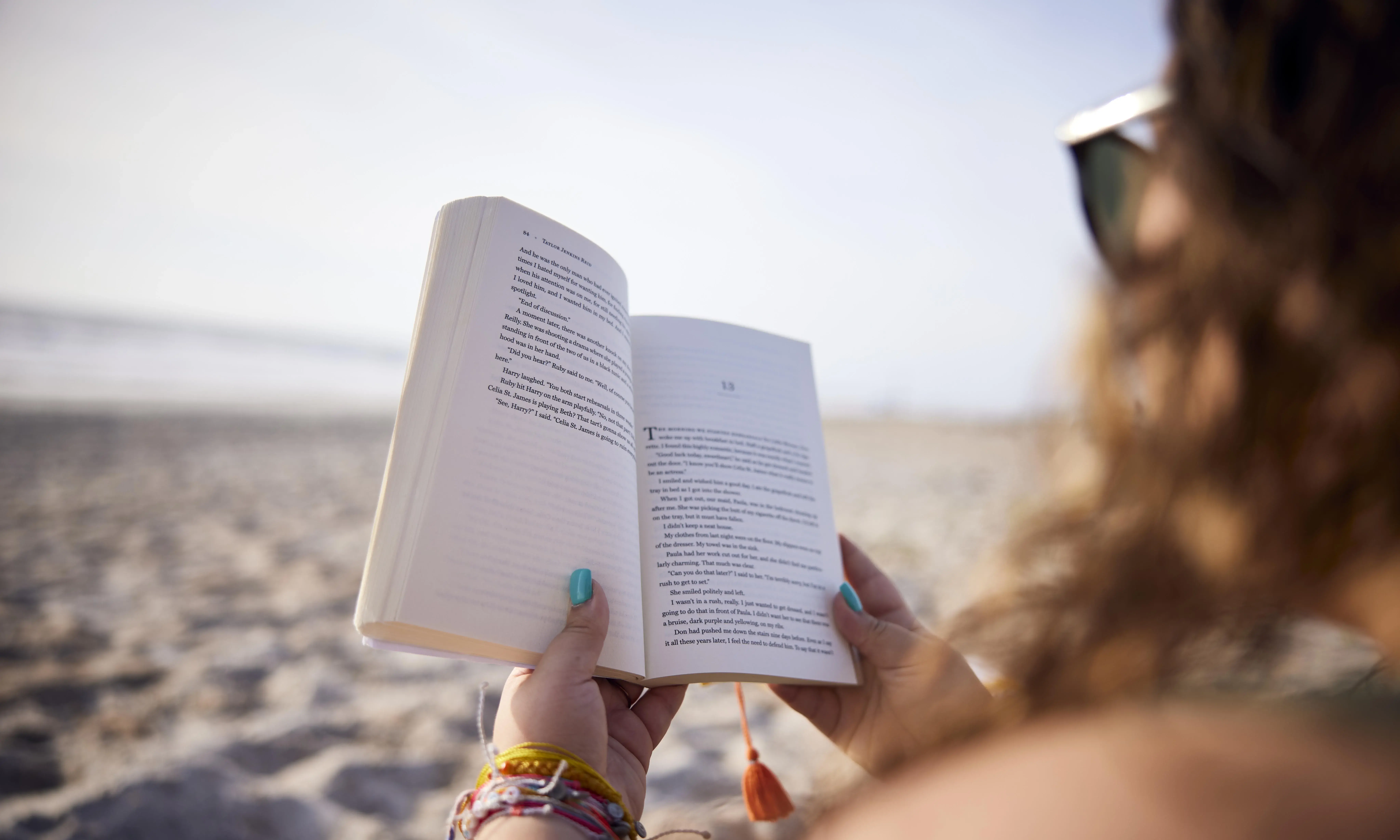 Student reading a book on the beach.