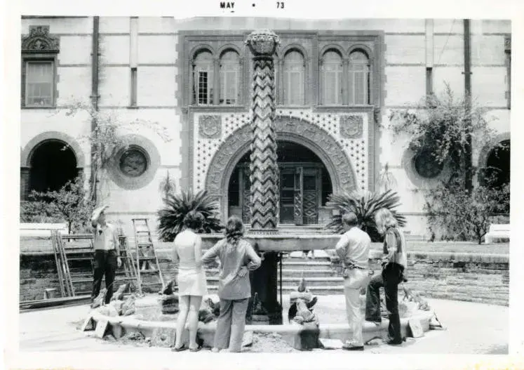 Black and white image of early Ponce. Several people are standing around the water fountain in the courtyard.