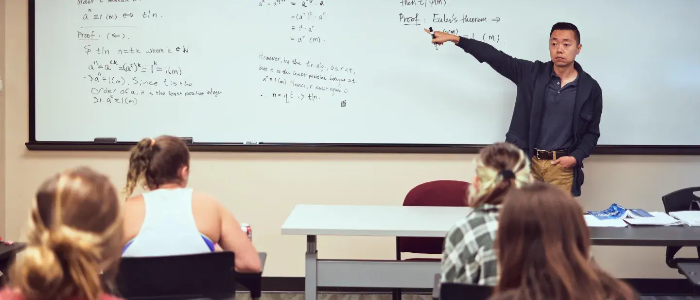 A Flagler College faculty member instructs using a white board.