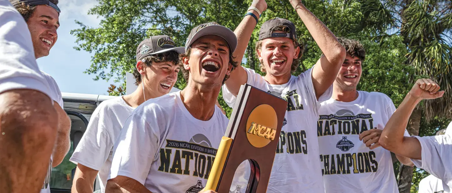 Men's tennis team holding their trophy and celebrating their championship win