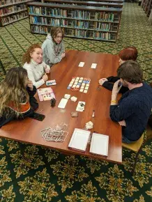 Students playing a game at a table in a library