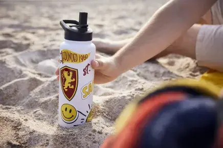 Flagler-decorated water bottle resting in sand at beach