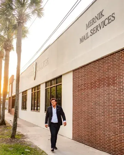 Jimmy Mernik posing at sunset in front of Mail Services building in his name