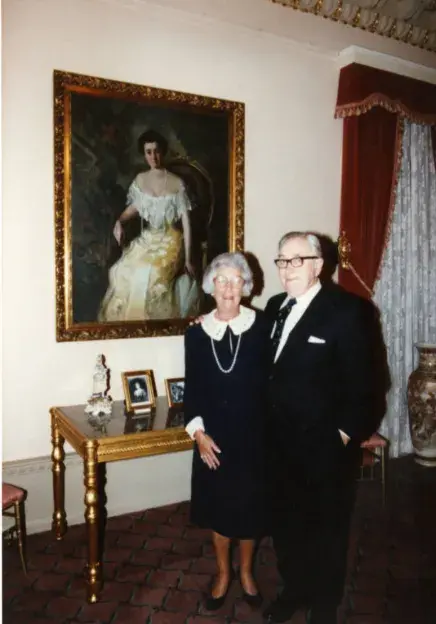 Molly and brother standing beside a portrait of Mary Lily Kenan Flagler