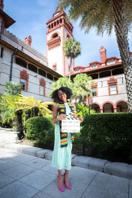 Ashley Chatmon holding a clapper board in the Ponce courtyard