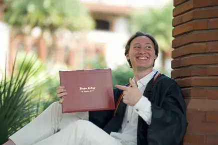 Gabe with diploma sitting in archway