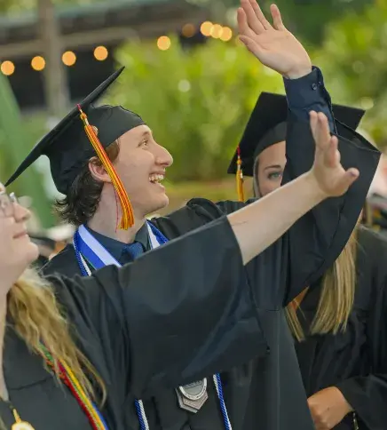 Gabe smiling, waving at Commencement crowd