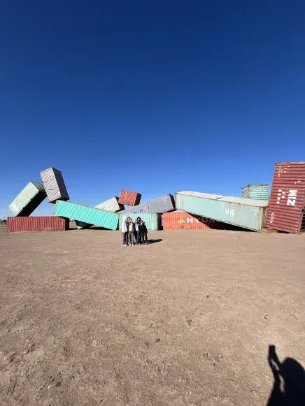 Group in front of large art installment in the desert.