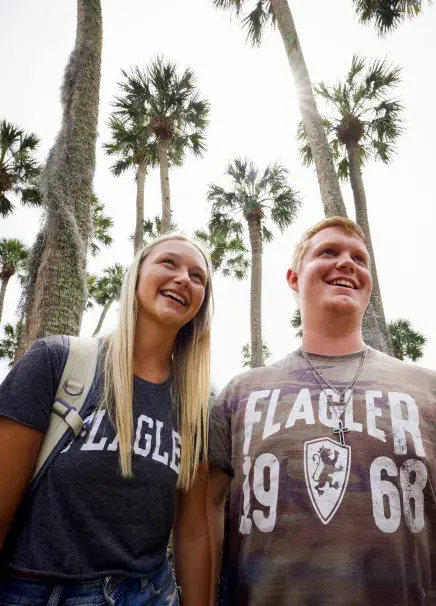 Two students in front of palm trees