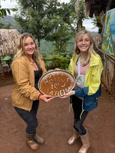 Nateleigh Nachreiner holding a plate with her name written in the coffee dust with another female student