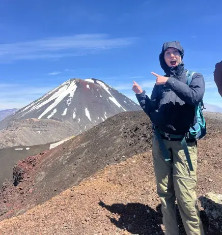 Katie Kress stands with a look of amazement while she points at a snow capped mountain in the background