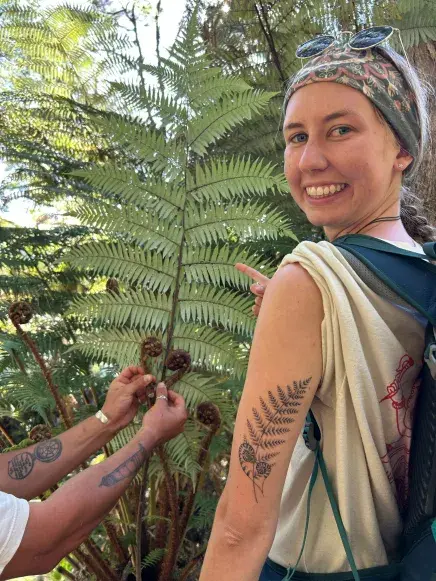 Katie Kress stands next to a Silver Fern which is native to New Zealand, which she also has a tattoo of on her arm