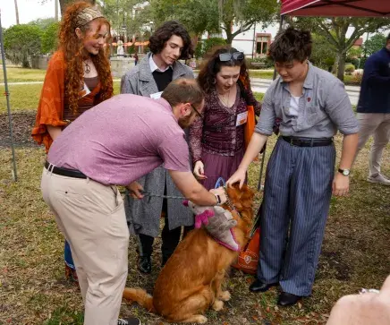 A group of newly admitted students gather around Bodhi the Golden Retriever