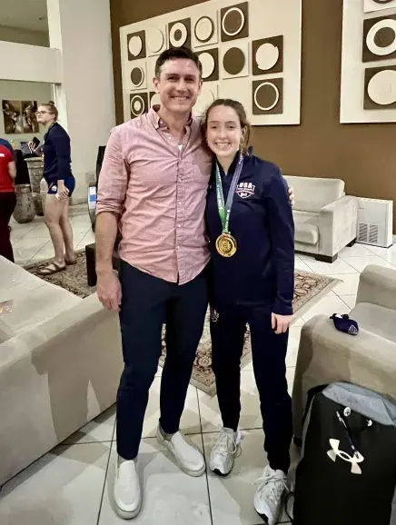 Maddie Nilan standing with an older man with a medal from the 2022 Deaflympics around her neck