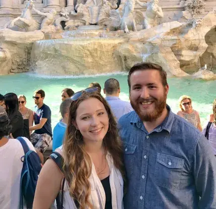 Carie and Zach Moore standing in front of a fountain in Rome, Italy.