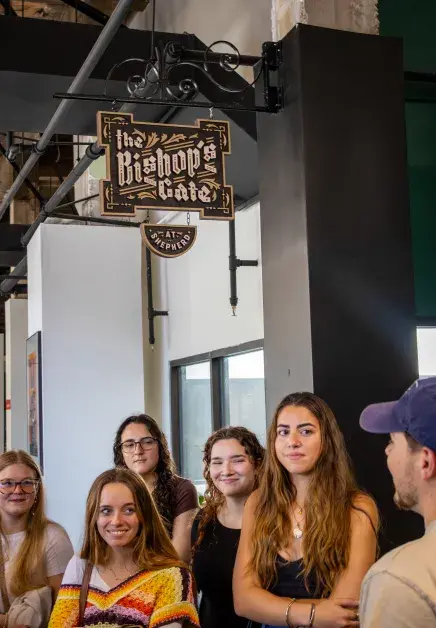 students on a tour group up beneath a sign to listen to the guide