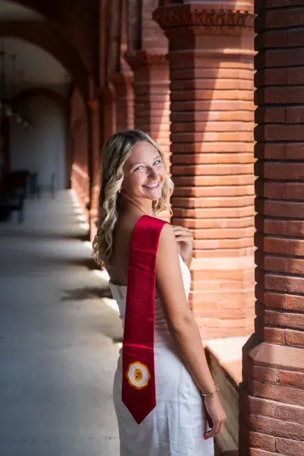 Carly Stern looks back over her shoulder with a graduation stole hung over her shoulder