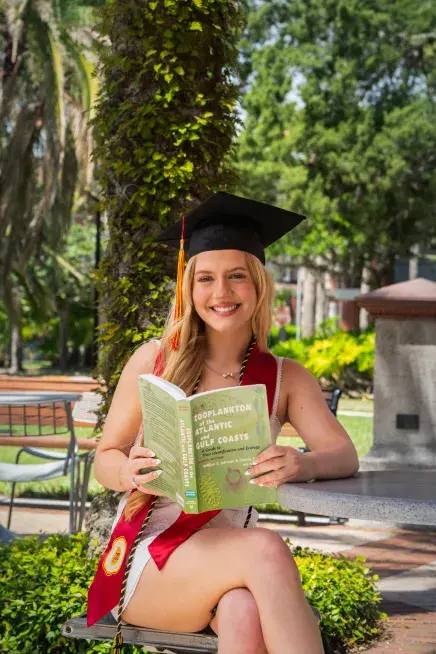 Ava Mantha seated holding a natural sciences textbook