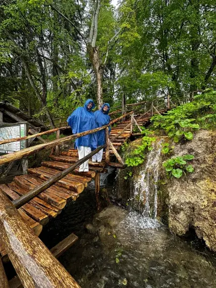 Two students pose in the rain while wearing ponchos at Plitvice National Park in Croatia