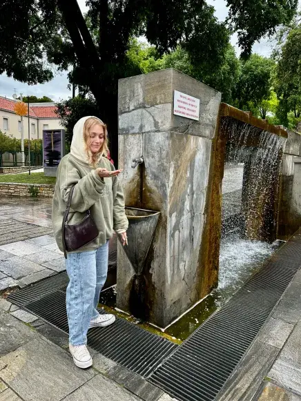 A student grabs water from an ancient water fountain