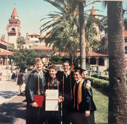 Ernie Costello with friends in cap and gowns in front of the Ponce
