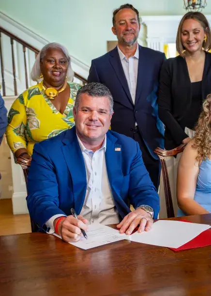 Scott Sturgill smiles at camera while signing his gift agreement