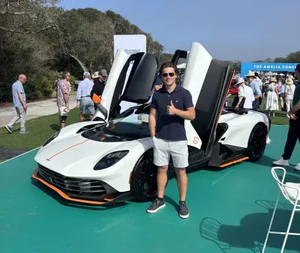 Logan Sarosi standing in front of a luxury car