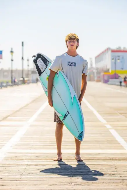 Mitch Zappone stands with his surfboard