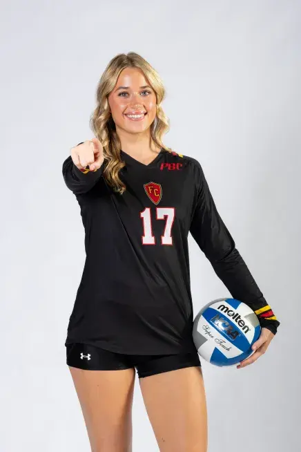 Jilly Young stands with a volleyball and points towards the camera