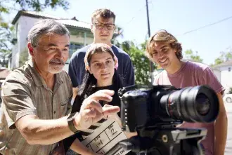 A faculty member shows students how to use a camera.