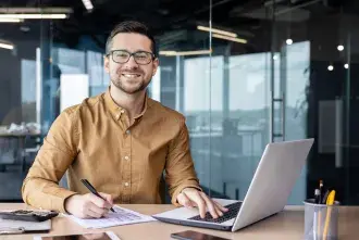 A student with a laptop smiles.