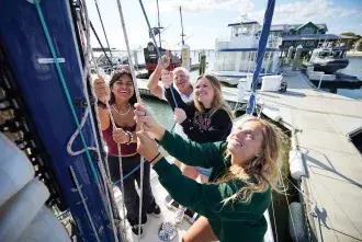 Students raising a sail on a boat.