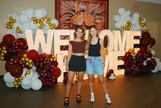 Students posing in front of Welcome Home sign