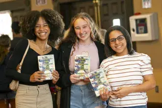 Three female students holding Zevin's novel smiling for group photo
