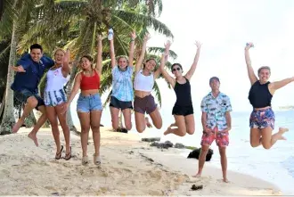 Flagler College students jump in the air on the beach.