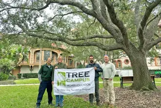Tree Campus Banner held by members of the advisory board on west lawn