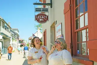 Nikki L. and Sam P. posing in front of the Legacy with 25th anniversary t-shirts and birthday hats