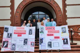 Students with final poster presentations posed in front of Proctor