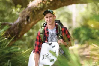 Professor Sam McMillan holding a surfboard