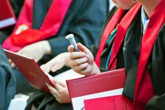 Spike and diploma in the hand of sitting graduate at a recent Commencement