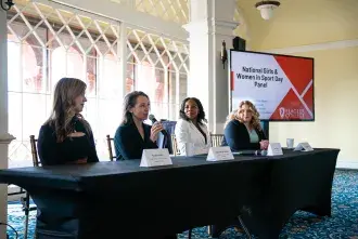 The four panel speakers sit at the front of the room for National Women and Girls in Sport Day