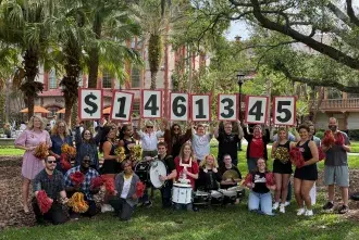 Roar Raise Announcement - group of students and staff holding numbers showing the total dollars raised