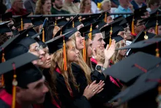 A group of graduates look up from the crowd