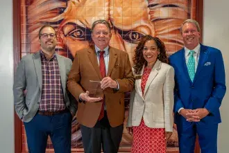 President John Delaney, Vice President & Chief Human Resources Officer Kelly Toaston, Compensation and Benefits Campus Partner Hayden George, and Trustee Mark Bailey Sr pose with the wellness award