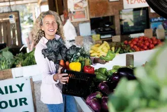 Dr. Carrie Grant holding a basket of vegetables at a market