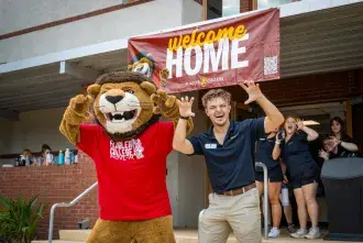 Joseph DelliSanti stands with Lewis The Lion while moving residents into Cedar Hall