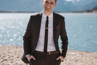 Derek Boik standing on a beach with snow-capped mountains in the background