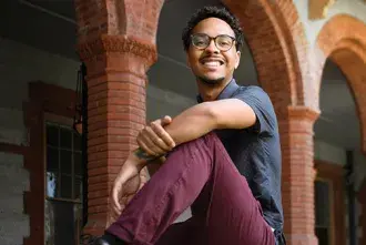 Flagler College student, Spencer Hooker, sitting on a wall near Ponce Hall